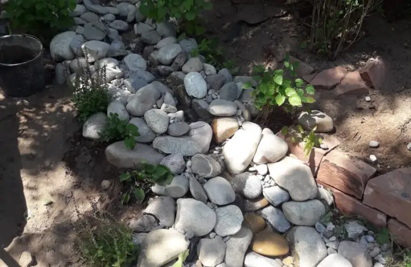 Kiesrinne mit Flusskieseln, die Regenwasser durch den Garten führt