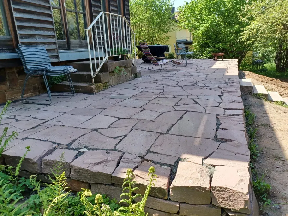 Terrasse aus Sandstein-Polygonalplatten mit offenen Fugen auf einer Trockenmauer
