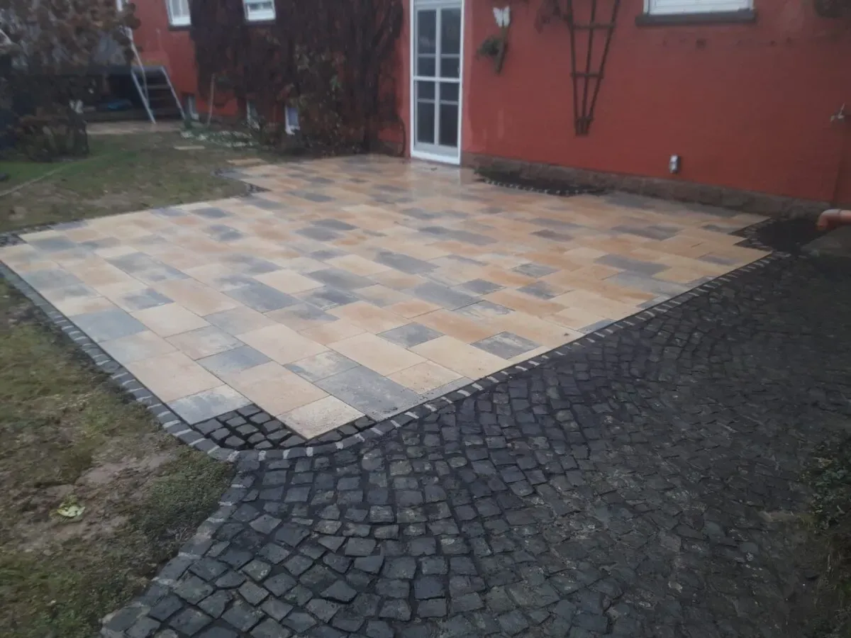 Terrasse aus Betonsteinplatten mit Einfassung und Anschlussfläche aus Granitpflaster