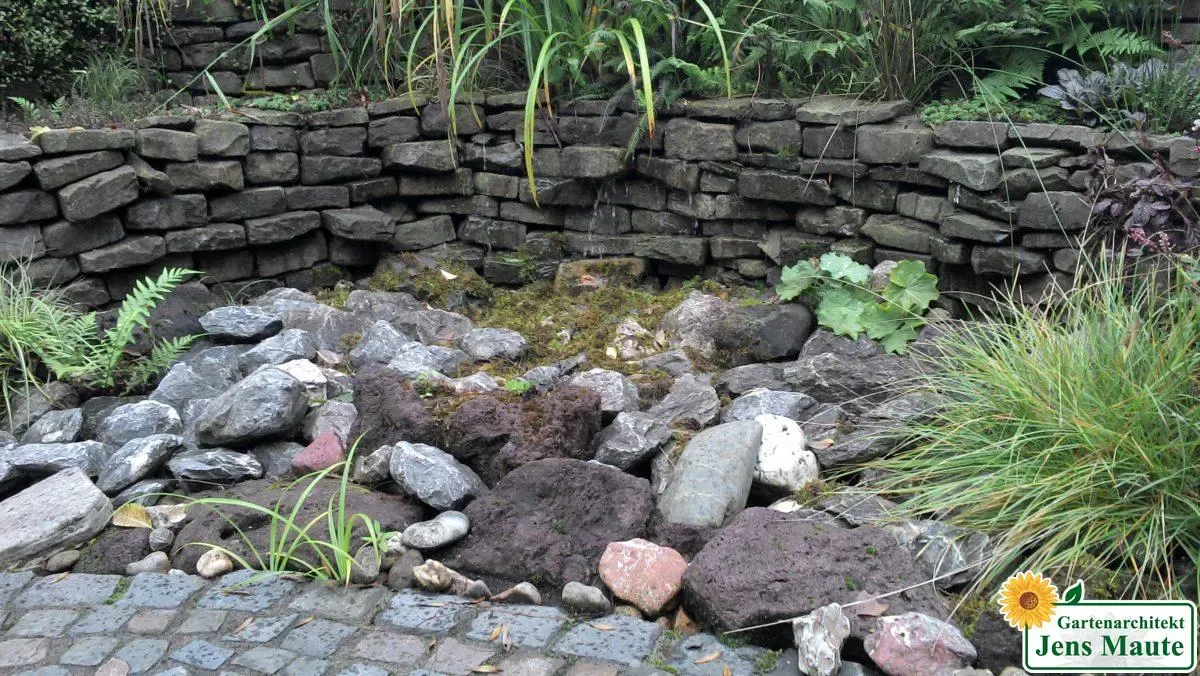 Gartenteich, eingefasst von einer Trockenmauer aus Naturstein