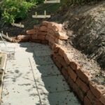 Weg aus Betonplatten und Stützmauern aus Sandstein